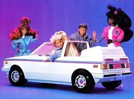 Barbie and three friends clas in 1980s attire and big hair sit in a white convertible